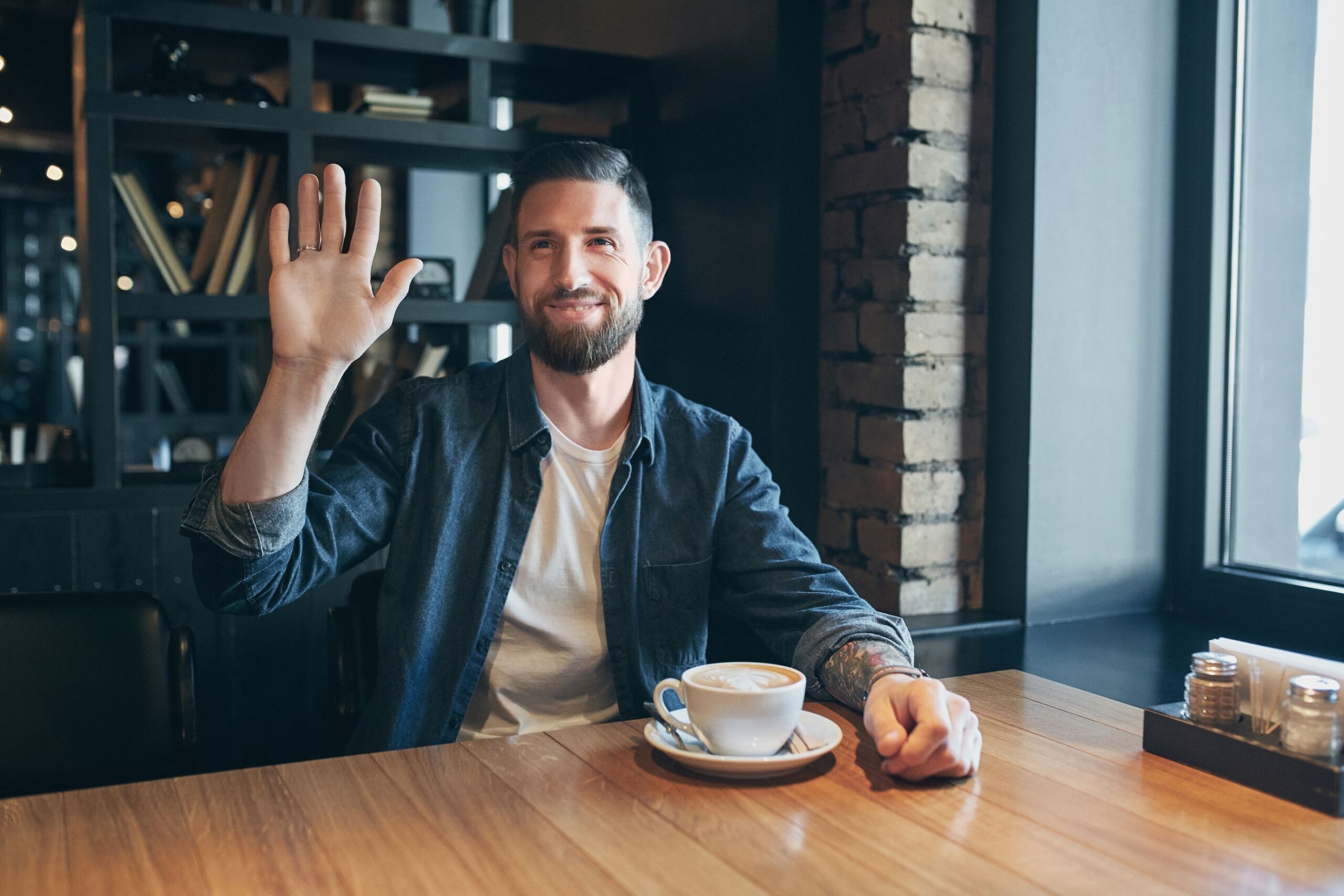 Young happy bearded man drinking morning fresh coffee. Say hello
