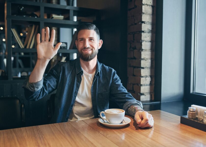 Young happy bearded man drinking morning fresh coffee. Say hello